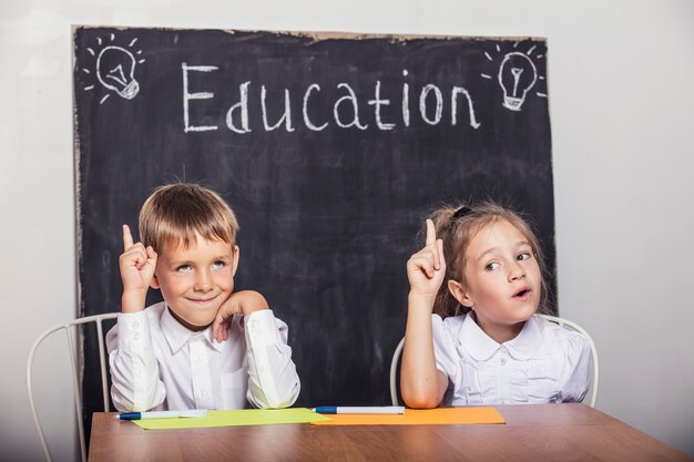 Estudiantes en la clase en el escritorio contra la pizarra