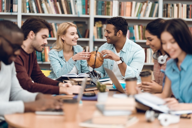 Los estudiantes están hablando y leyendo en la biblioteca.