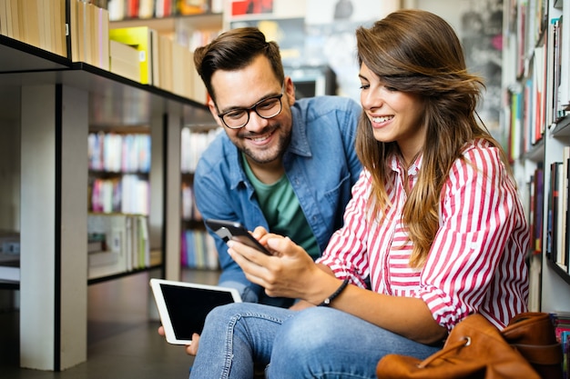 Los estudiantes estudian juntos en la biblioteca. Pareja, estudio, tecnología, educación amor concepto