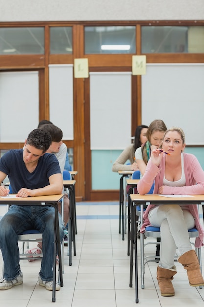 Foto estudiantes en un examen mientras uno está pensando