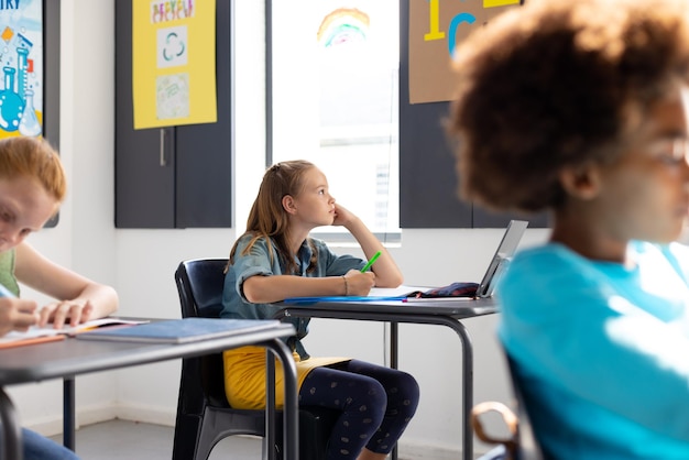 Estudiantes felices y diversos sentados en los escritorios de las aulas de la escuela