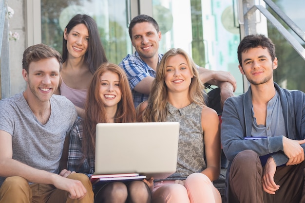 Estudiantes felices sonriendo a la cámara afuera en el campus