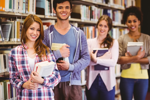 Estudiantes felices sosteniendo libros en fila