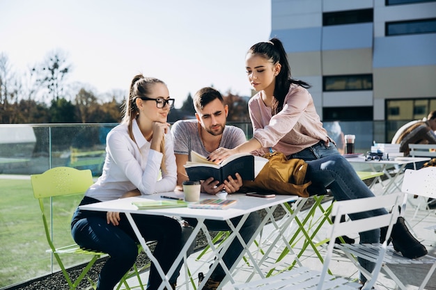 Los estudiantes felices trabajan y estudian en la mesa al aire libre