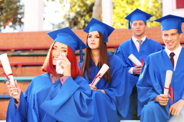 Estudiantes graduados con toga y sombrero de graduación al aire libre