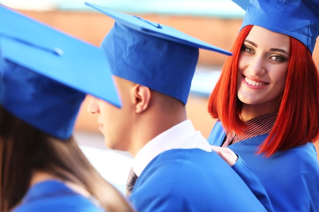 Estudiantes graduados con toga y sombrero de graduación al aire libre