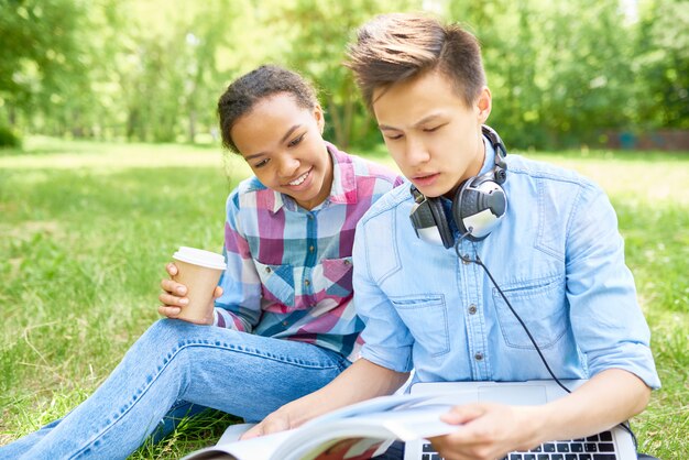 Foto estudiantes haciendo la tarea al aire libre en el césped