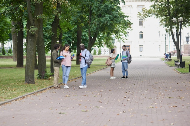 Estudiantes interraciales felices con cuadernos en un parque de verano