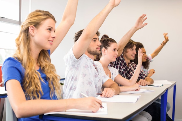 Estudiantes levantando las manos en el aula