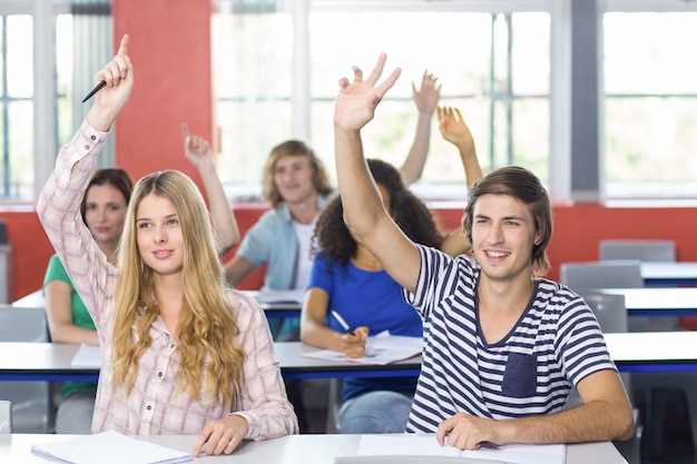 Estudiantes levantando las manos en el aula