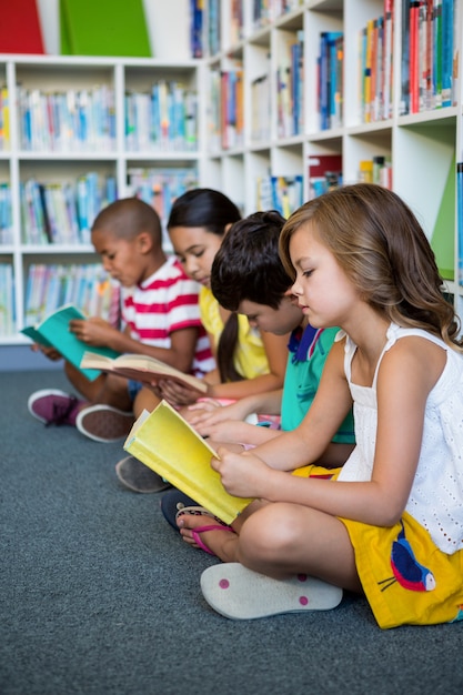 Estudiantes leyendo libros mientras están sentados en la biblioteca