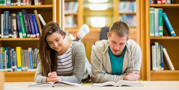 Estudiantes leyendo libros en el piso de la biblioteca