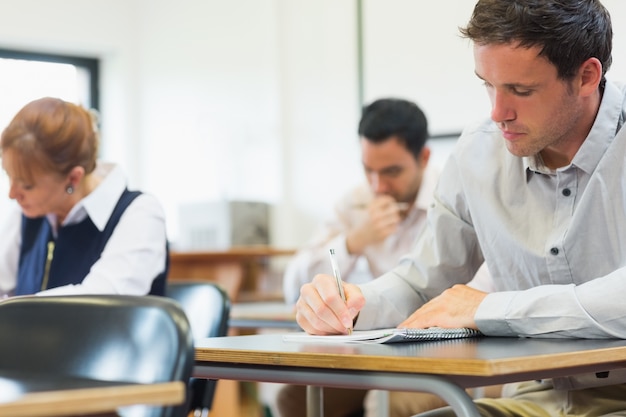 Estudiantes maduros tomando notas en el aula