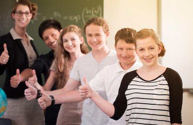 Los estudiantes y el maestro de la clase de la escuela se paran frente a una pizarra con el trabajo de matemáticas en un aula durante la lección