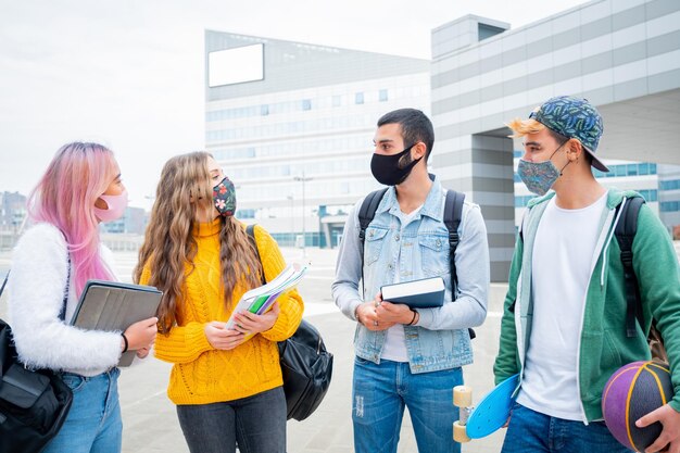 Estudiantes con máscaras discutiendo mientras están de pie en el campus