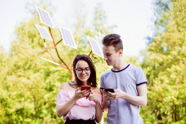 Estudiantes masculinos y femeninos contra paneles solares usando dispositivos modernos