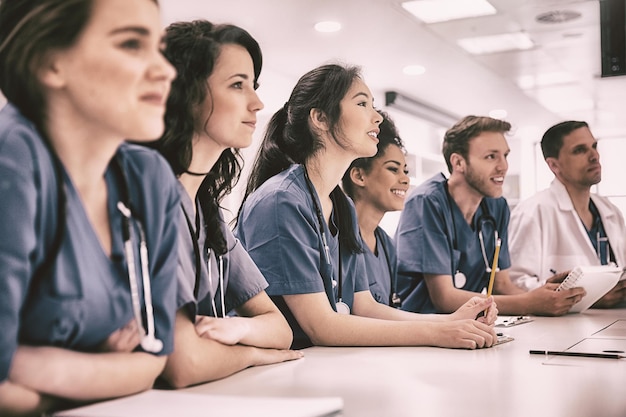 Estudiantes de medicina escuchando sentados en un escritorio en la universidad