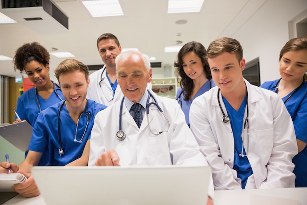 Estudiantes de medicina y profesor usando laptop