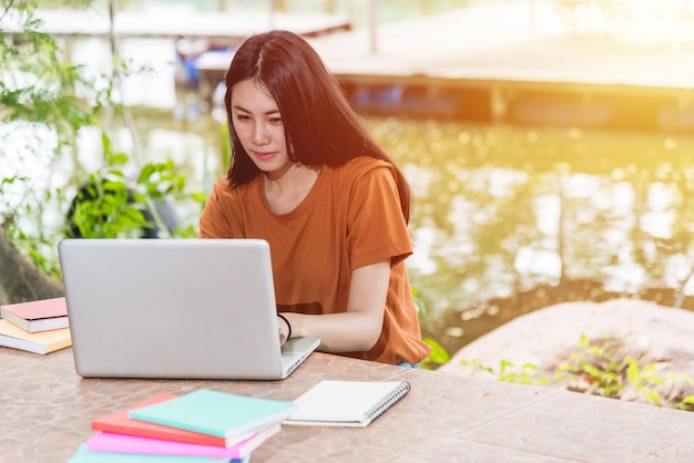 Estudiantes mujeres están usando computadora portátil al aire libre, concepto de educación