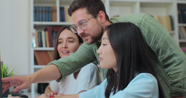 Foto los estudiantes multiculturales estudian para los exámenes en equipo usan la computadora hablan buscan una solución explican el tema los estudiantes universitarios trabajan juntos