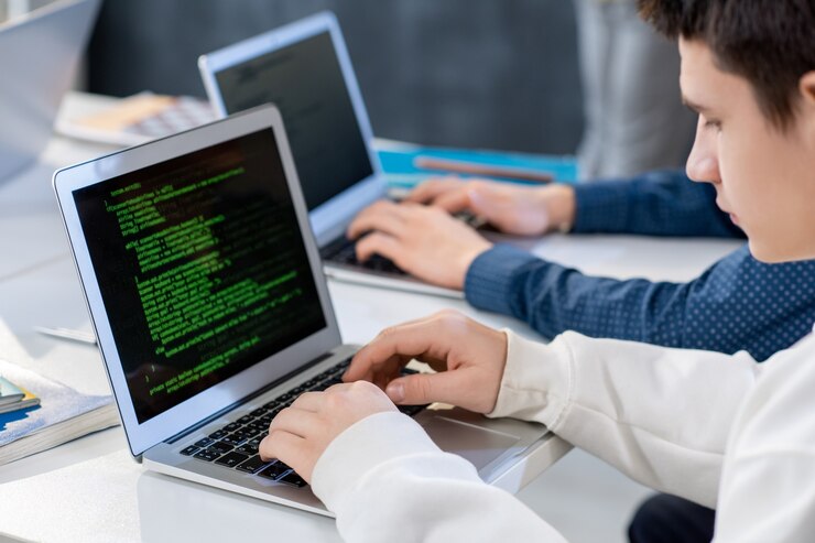 Foto uno de los estudiantes o programadores frente a la computadora portátil ingresando datos técnicos mientras mira la pantalla durante el trabajo sobre un nuevo software