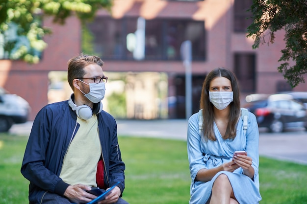 Estudiantes pasando el rato en el campus con máscaras protectoras y manteniendo distancia debido a la pandemia de coronavirus