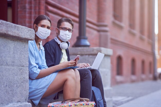 Estudiantes pasando el rato en el campus con máscaras protectoras y manteniendo distancia debido a la pandemia de coronavirus