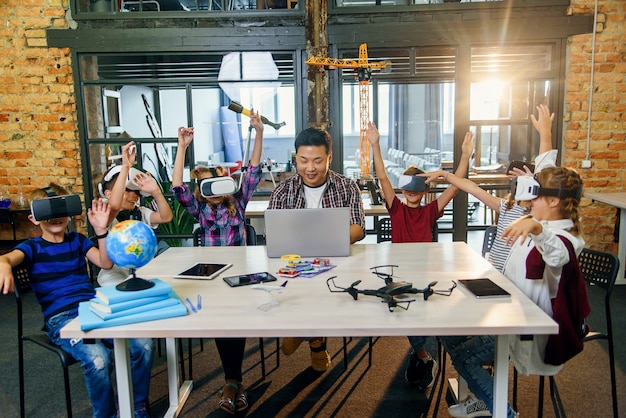 Estudiantes preadolescentes que utilizan la realidad aumentada para estudiar en una escuela inteligente moderna. Grupo de alumnos con auriculares VR durante una clase de informática.