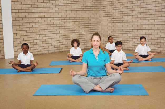 Estudiantes y profesor haciendo yoga plantean