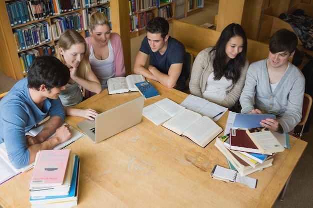 Foto estudiantes que aprenden con una computadora portátil y una tableta en una biblioteca