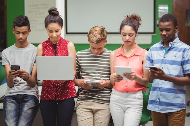 Estudiantes que usan computadora portátil, teléfono móvil, tableta digital