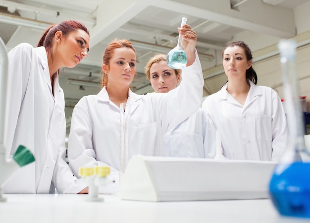 Foto estudiantes de química mirando un líquido