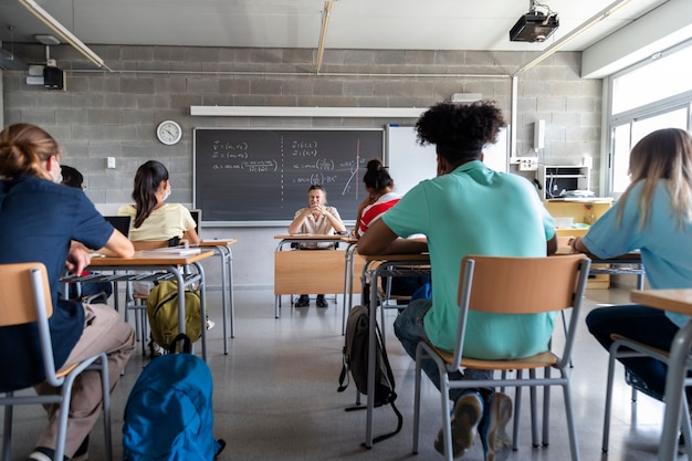 Los estudiantes de secundaria de adolescentes multirraciales en el aula con espacio de copia de maestro blanco maduro