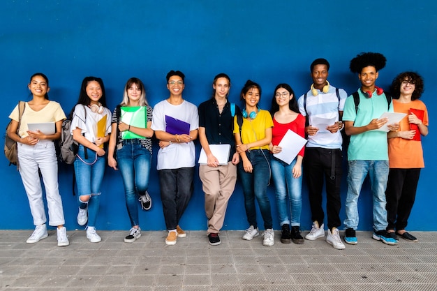 Estudiantes de secundaria multirracial mirando a la cámara sobre fondo azul Educación de regreso a la escuela