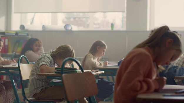 Estudiantes sentados en escritorios en la clase de la escuela Niños teniendo una lección en el aula