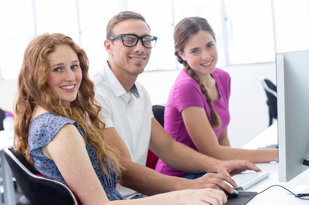 Estudiantes sonriendo a la cámara en clase de informática