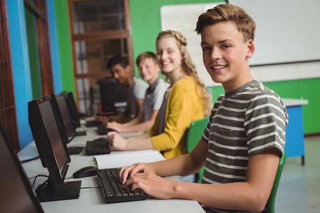 Estudiantes sonrientes estudiando en la clase de computadoras