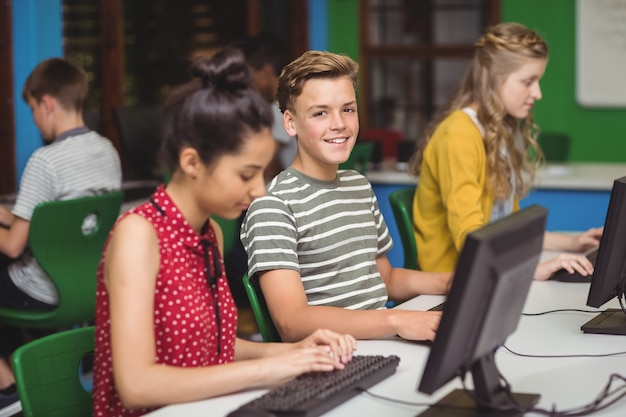 Estudiantes sonrientes estudiando en la clase de computadoras