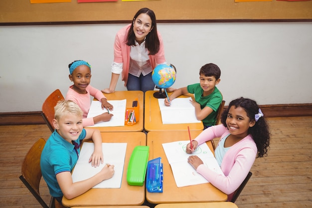 Estudiantes sonrientes y profesor mirando la cámara
