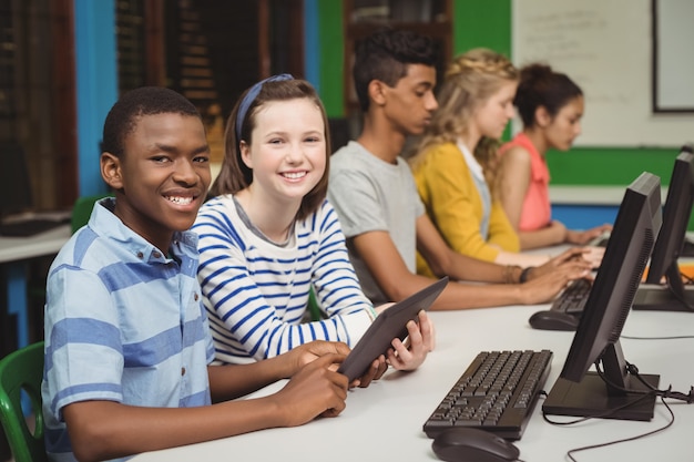 Estudiantes sonrientes que estudian en el aula de informática