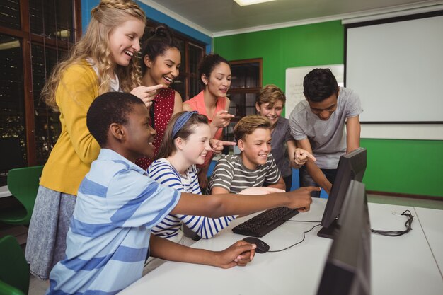 Estudiantes sonrientes que estudian juntos en el aula de informática