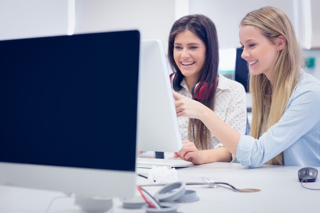 Estudiantes sonrientes usando la computadora en la universidad