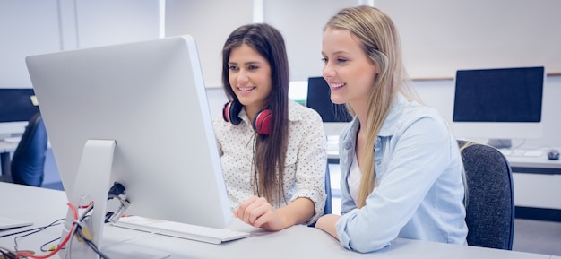 Estudiantes sonrientes usando la computadora en la universidad