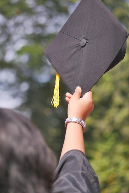 Los estudiantes sostienen sombreros en la mano durante el éxito de la ceremonia de graduación con antecedentes amarillos