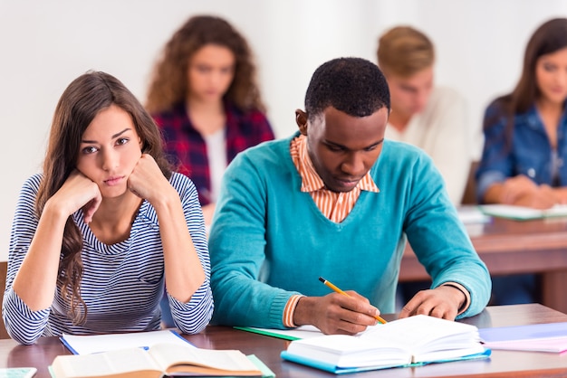 Los estudiantes tristes se sientan en sus escritorios y estudian.