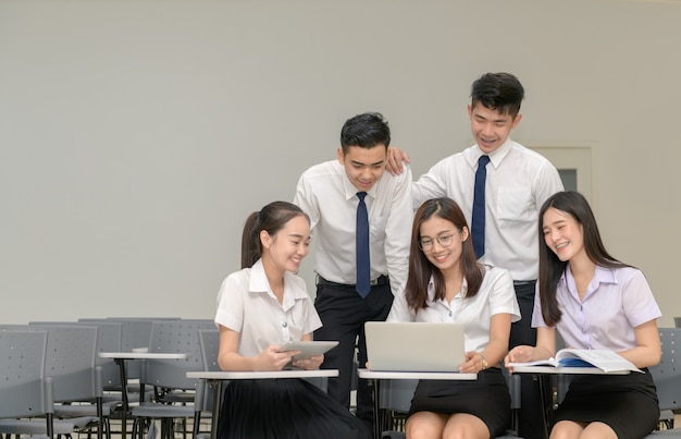Estudiantes en uniforme trabajando con laptop.