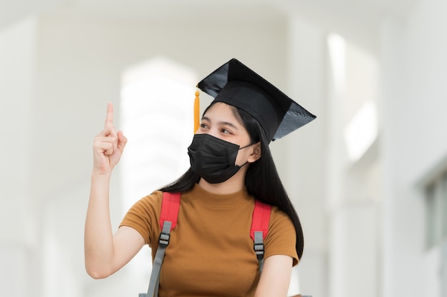 Las estudiantes universitarias, graduadas universitarias, visten sombreros negros, borlas amarillas y visten máscaras durante la epidemia.