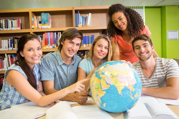 Foto estudiantes universitarios apuntando al mundo en la biblioteca