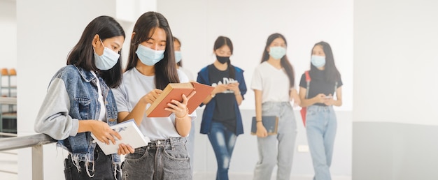 Estudiantes universitarios asiáticos de regreso a la escuela con mascarilla protectora estudiando en el campus