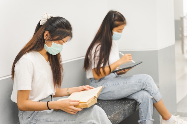 Estudiantes universitarios asiáticos de regreso a la escuela con mascarilla protectora estudiando en el campus